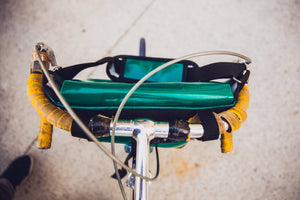 Sac messenger Dababo, modèle Transporter M avec option pour vélo. Attache poitrine à clips et attaches cadre velo. Couleur bleu ciel. Sac attaché au guidon du vélo.