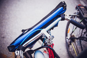 Sac messenger Dababo, modèle Transporter L2 avec option pour vélo. Attache poitrine à clips et attache cadre velo. Couleur bleu ciel. Sac attaché au guidon du vélo.
