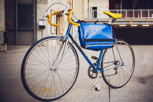 Sac messenger Dababo, modèle Transporter L2 avec option pour vélo. Attache poitrine à clips et attache cadre velo. Couleur bleu ciel sac attaché au cadre d'un vélo.