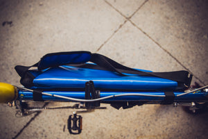Sac messenger Dababo, modèle Transporter L2 avec option pour vélo. Attache poitrine à clips et attache cadre velo. Couleur bleu ciel. Sac attaché au guidon du vélo.