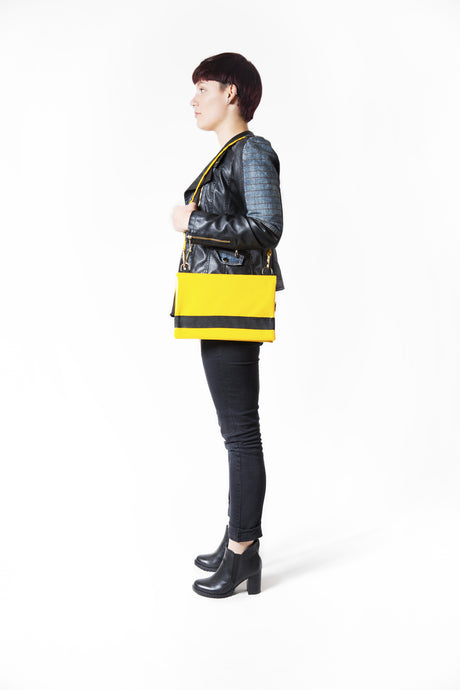 Sac de la marque Dababo, modèle Carnet jaune en chutes de bache de camions recyclées porté de profil à l'épaule par une femme