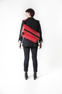 Sac messenger Dababo, modèle Transporter L2 rouge porté par une femme avec lanière de dos..