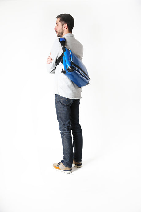 Sac messenger Dababo, modèle Transporter L2 avec option pour vélo. Attache poitrine à clips et attaches cadre velo. porté par un homme de profil. Couleur bleu clair.