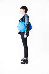 Sac à mains bleu-clair de la marque Dababo, modèle Everyday en chutes de bache de camions recyclées avec anse. Modèle féminin porté de profil à l'épaule